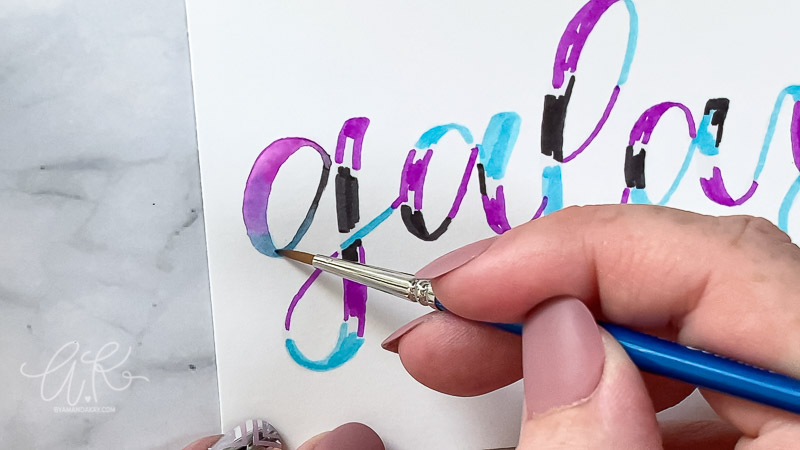 close up blending colors together with a brush on the letter "g"