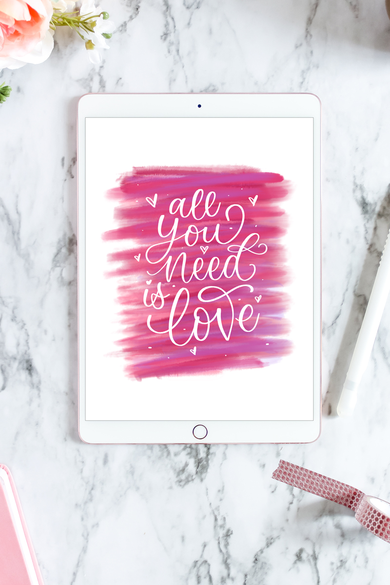 Digital "All you need is Love" artwork on an ipad on a marble backdrop with flowers and washi tape