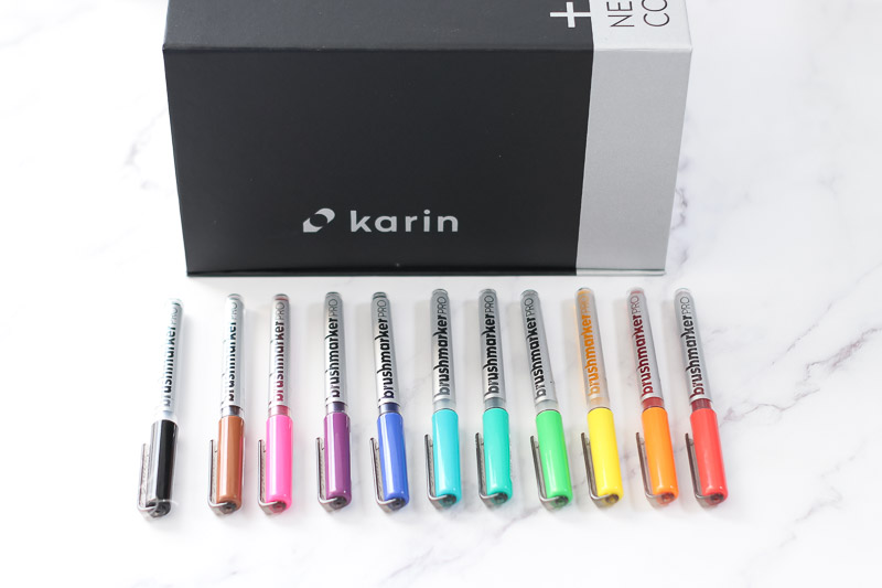 assorted karin brush markers laying on marble background